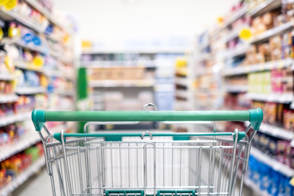Empty grocery cart in the middle of a grocery aisle.